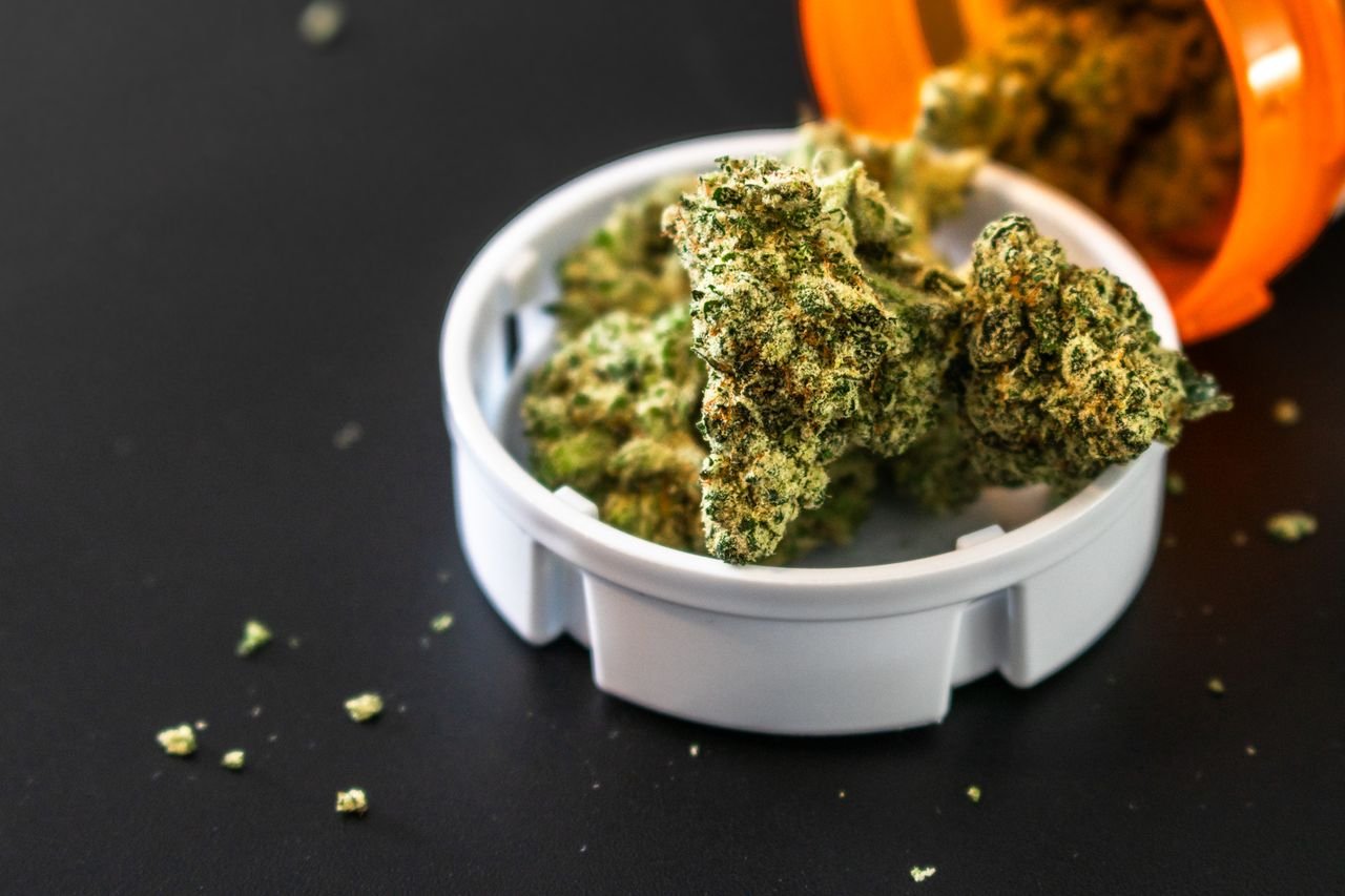 The Art of Drawing Readers In: Your attractive post title goes here Close-up of cannabis buds spilling from a prescription container, isolated on black background.